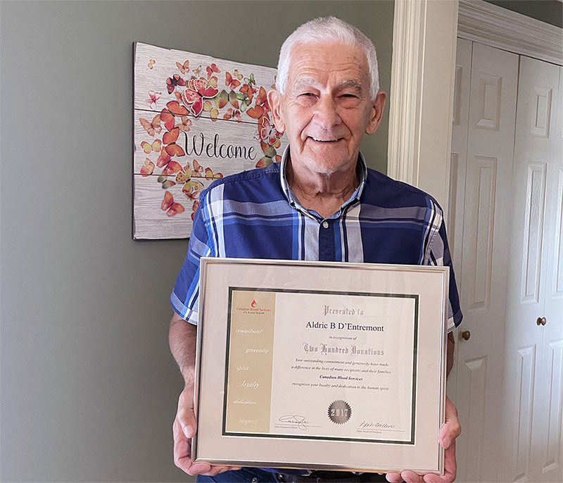 A blood donor holds a framed certificate
