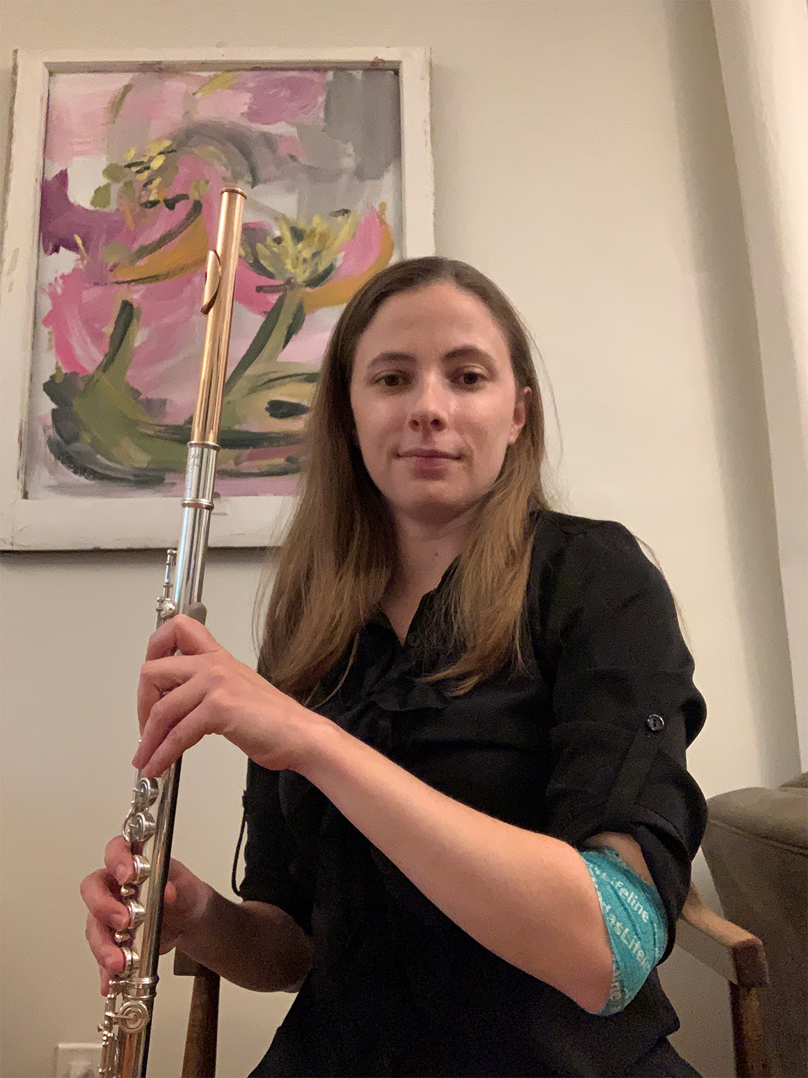 Image of Alex Conway holding a flute wearing a black shirt and with long brown hair.