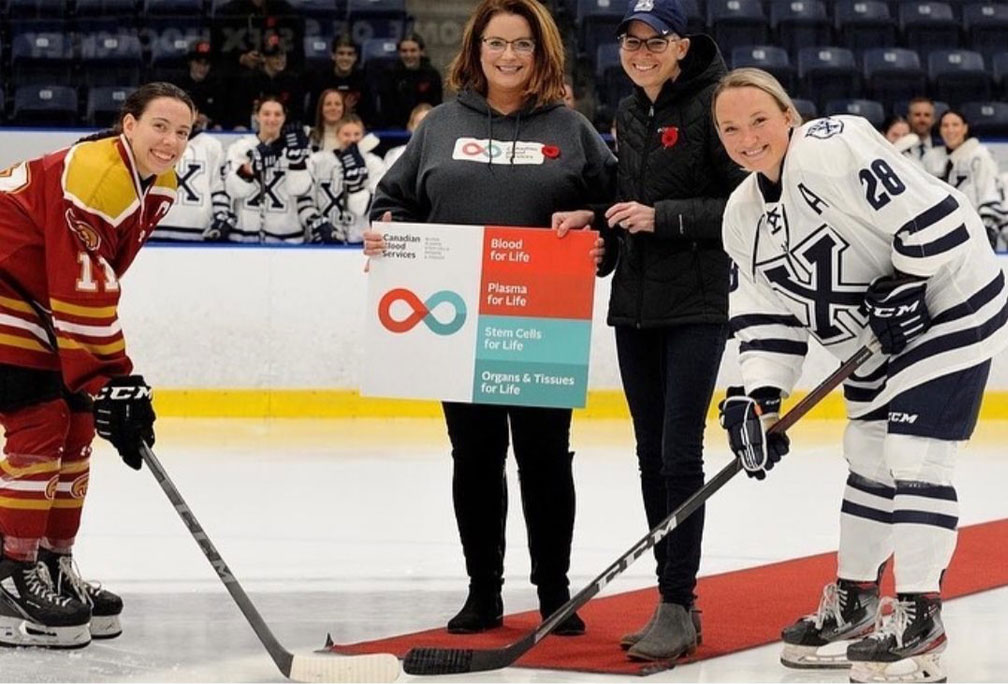Stem cell transplant recipient Gail Stewart posing for ceremonial puck drop at X-Women’s ice hockey game