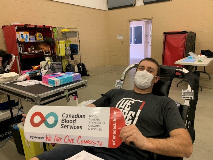 Dustin Windross holding up a sign donating blood.