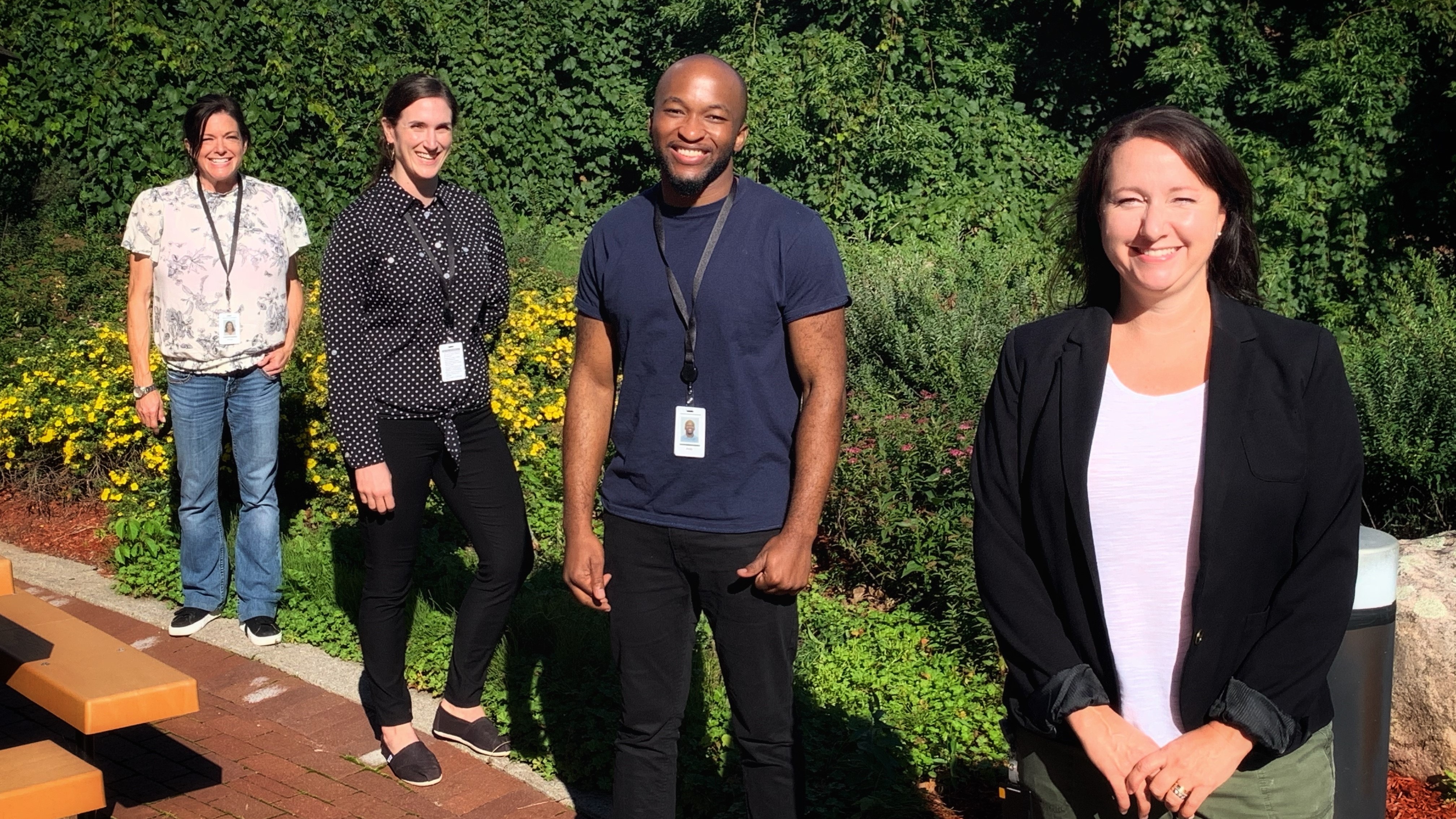 Image of Lab team members Stacey Vitali, Carissa Kohnen, Andy Tshiula Kalenga and Valerie Conrod standing outside of the office posing together with 2 metres apart