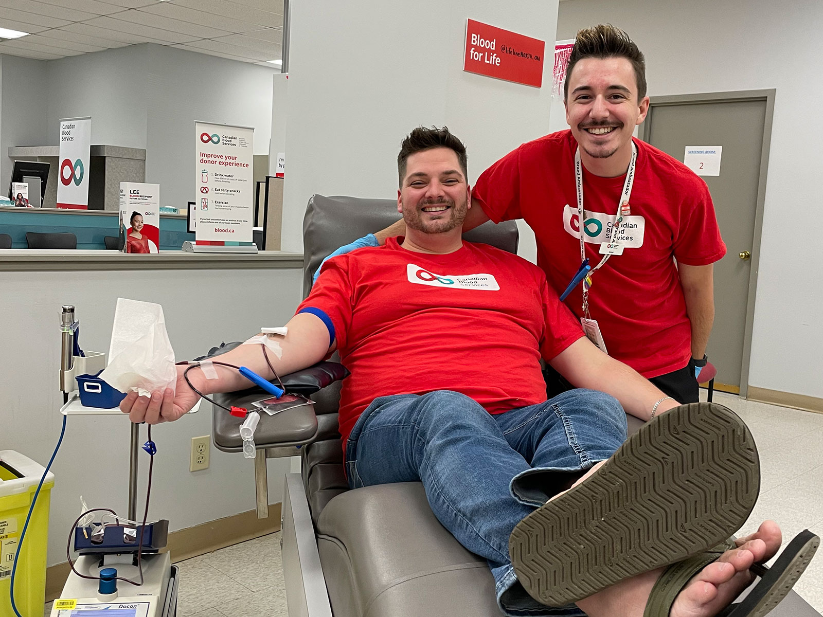 Man donating blood with partner smiling at his side