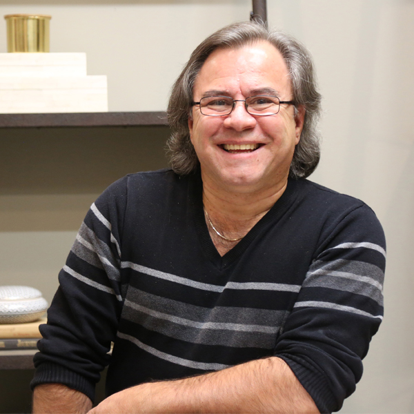 Image of blood donor Palmo Carpino sitting in front of a shelf wearing glasses and a striped sweater