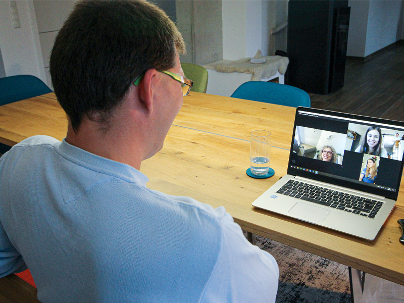 Image of Manuel sitting in front a computer at the dinner table chatting with Diane Charlebois and her daughters on Skype.