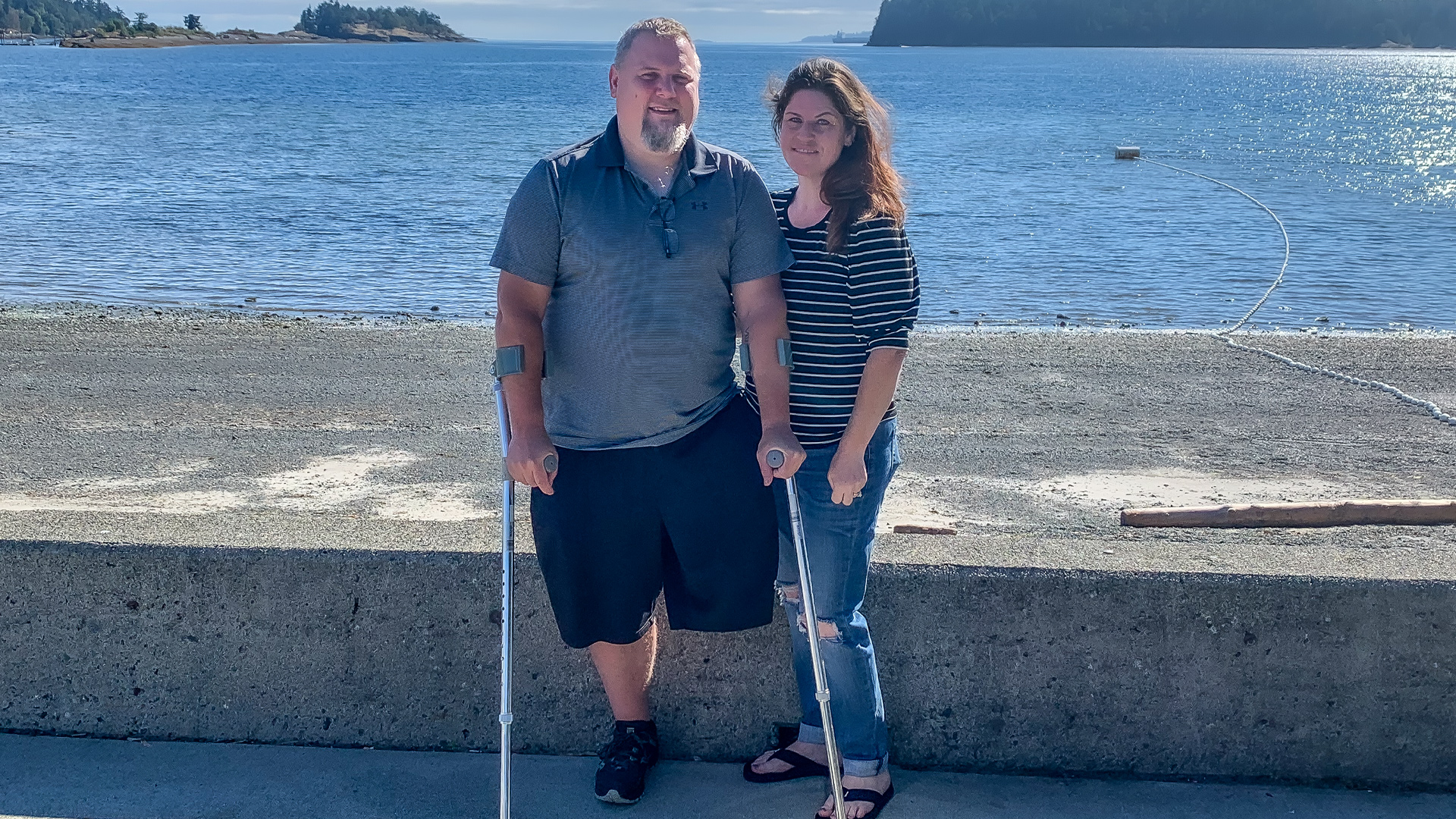 Image of blood recipient Nathan Olson on crutches and his wife Jennifer Olson posing together at the beach