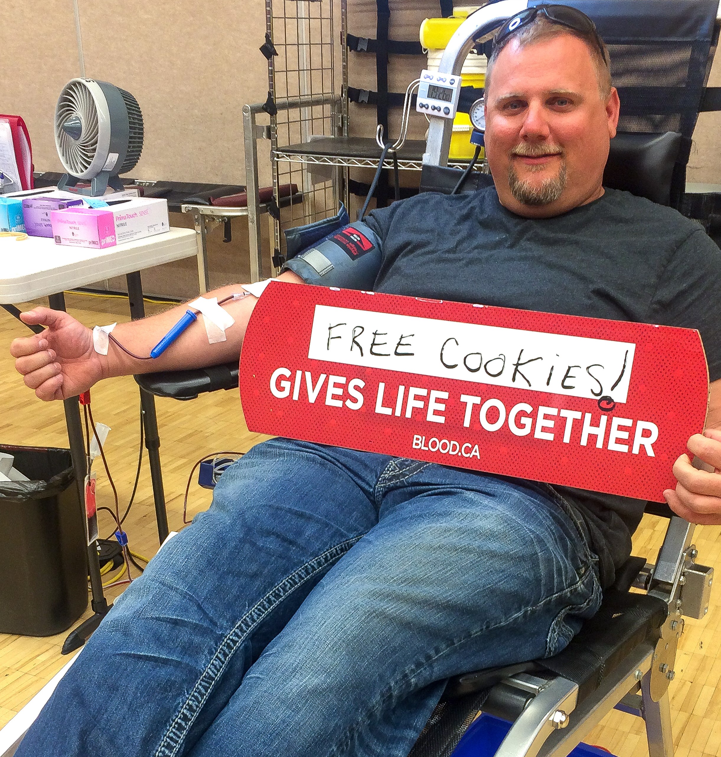 Image of blood recipient Nathan Olsan holding up a sign while sitting down to donate blood before his motorcycle crash.