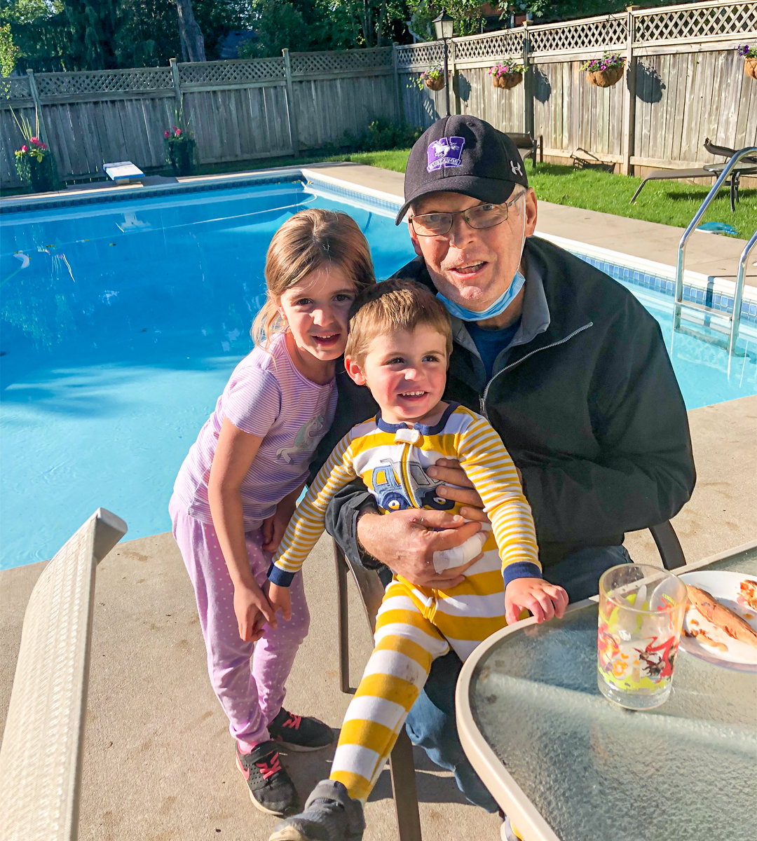 Image of Stem Cell recipient Peter Regan with his two grandchildren Sydney and Thomas Irvine sitting outside nearby a pool in the backyard