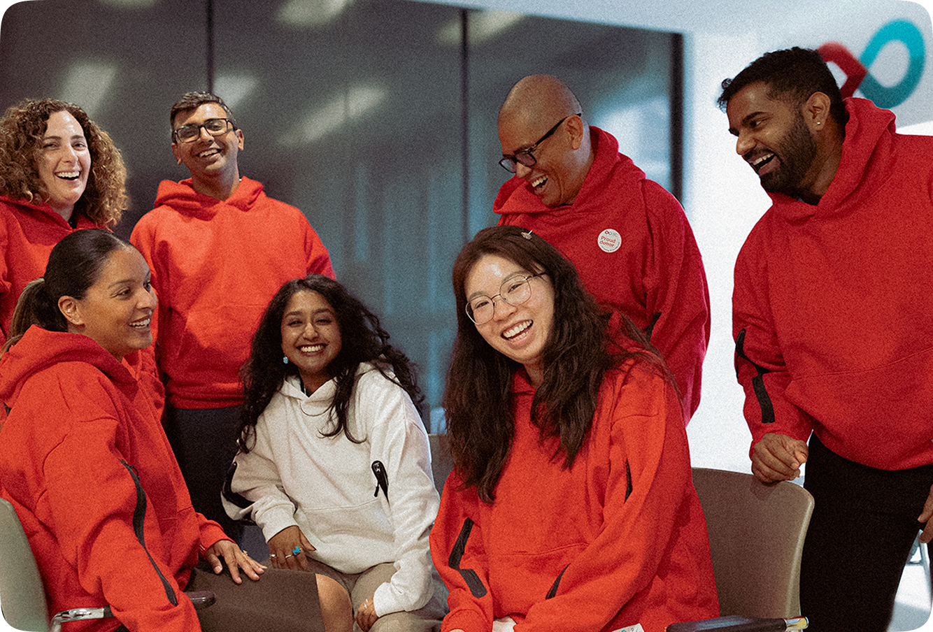 A group of seven young donors hanging out in a Canadian Blood Services donor centre, wearing red and white matching hoodies.