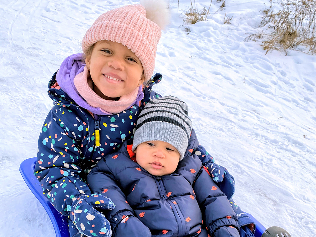 Jaida et Jakobe Greenidge, emmitouflés dans des habits de neige sur une luge.