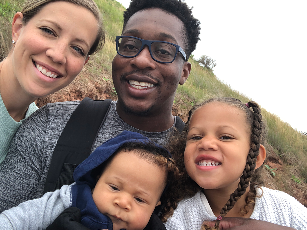 Laine and Jerald Greenidge with their children Jakobe and Jaida smiling outdoors.