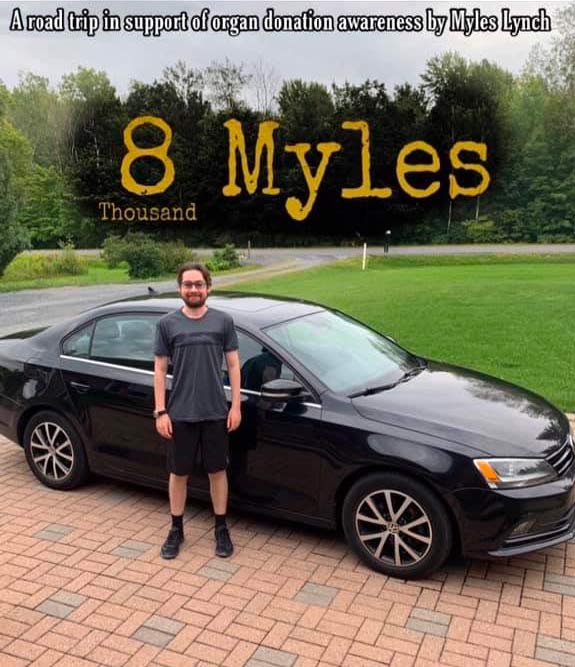 Myles Lynch smiles in front of black car while on road trip