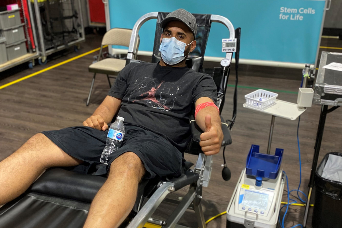 Man in shorts makes a blood donation as he rests in a donor bed