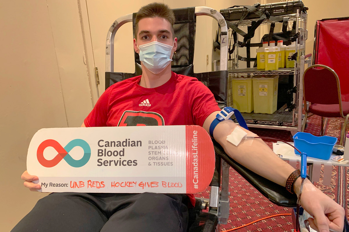 Ben Gagne of UNB Reds men's hockey team donating blood
