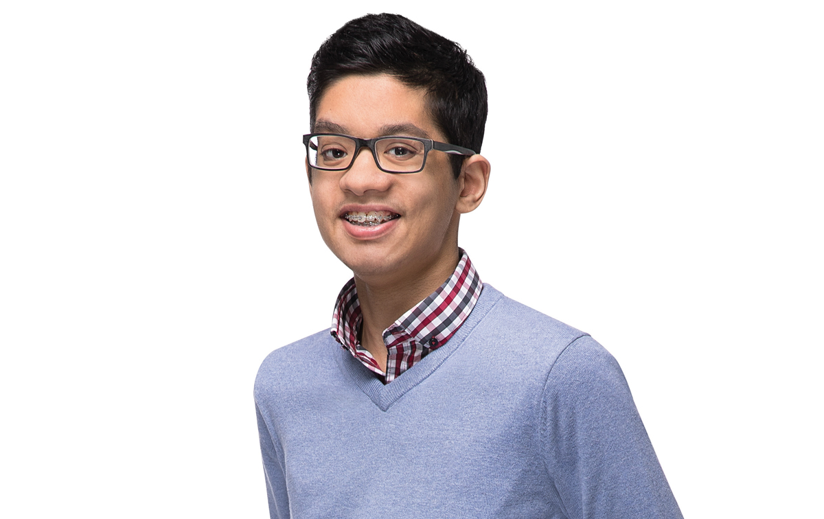 Image of Aizad with a lilac sweater on top of a plaid dress shirt wearing glasses on a white background