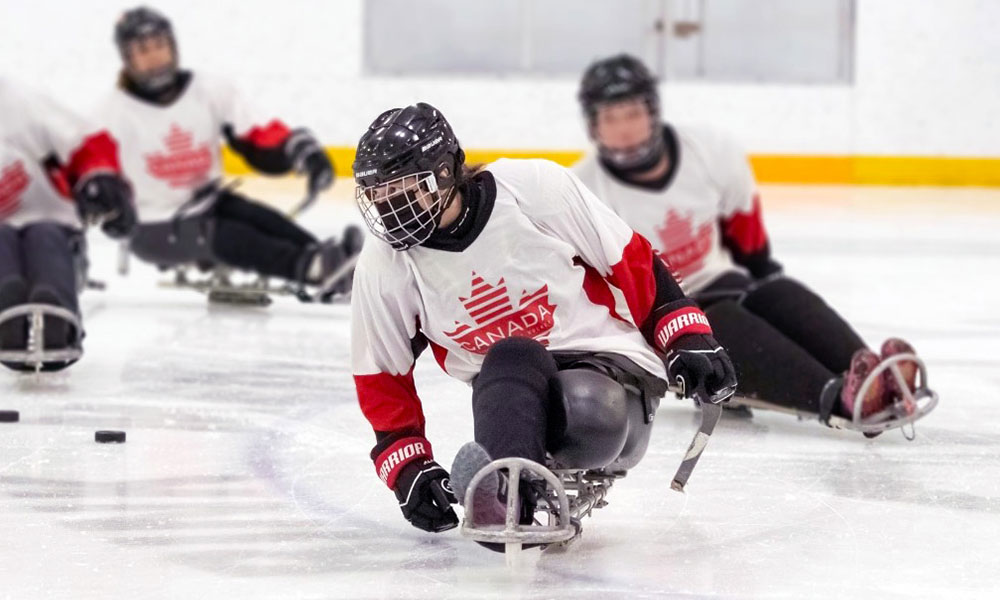 National team member Alicia Souveny playing para-hockey with teammates in action in the background