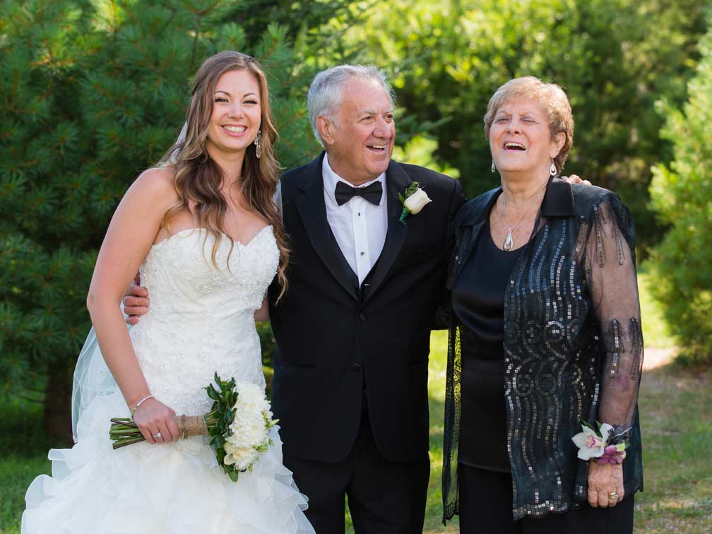 Bride holding bouquet with her grandfather and grandmother outdoors