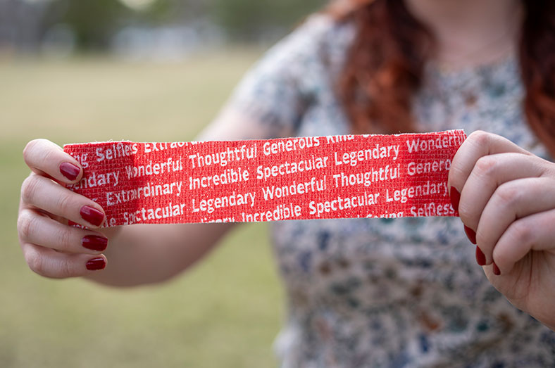 Person holding up a red bandage with words Spectactular, Incredible, Thoughtful, Wonderful