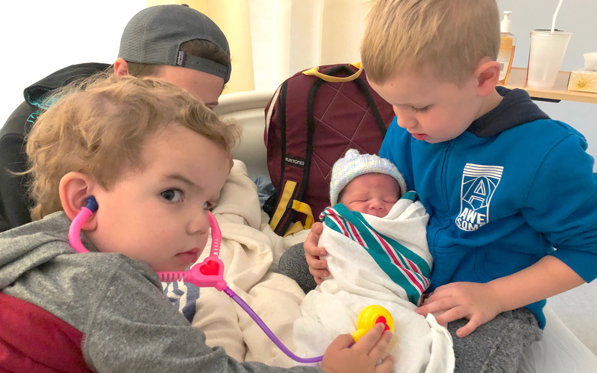 Donavan Does holds his baby brother Evander moments after he was born, as their other brother Austin checks baby’s pulse with a plastic stethoscope.