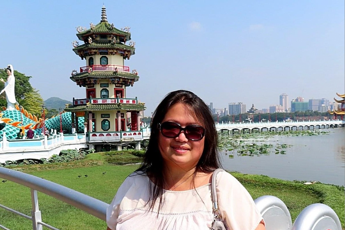 A Chinese woman in sunglasses stands in front of a pagoda in Taiwan.