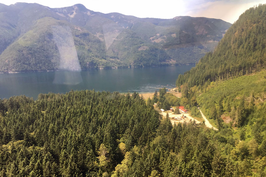 Forested bay area with logging camp buildings among trees