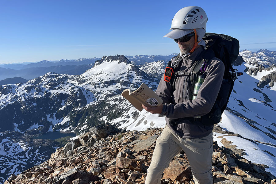 Man with backpack signing summit register in snowy mountains