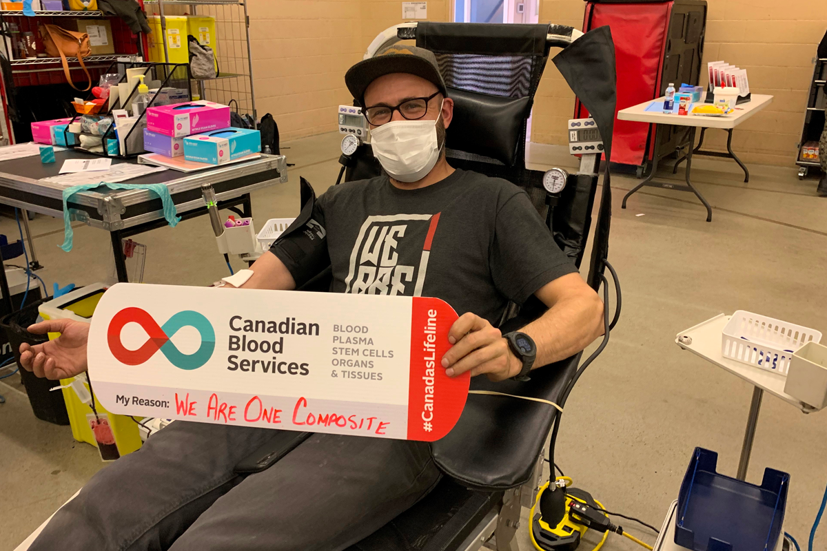 Man donates blood with Canadian Blood Services sign on his lap