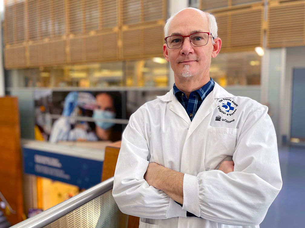 Doctor in lab coat with arms folded in hospital hallway