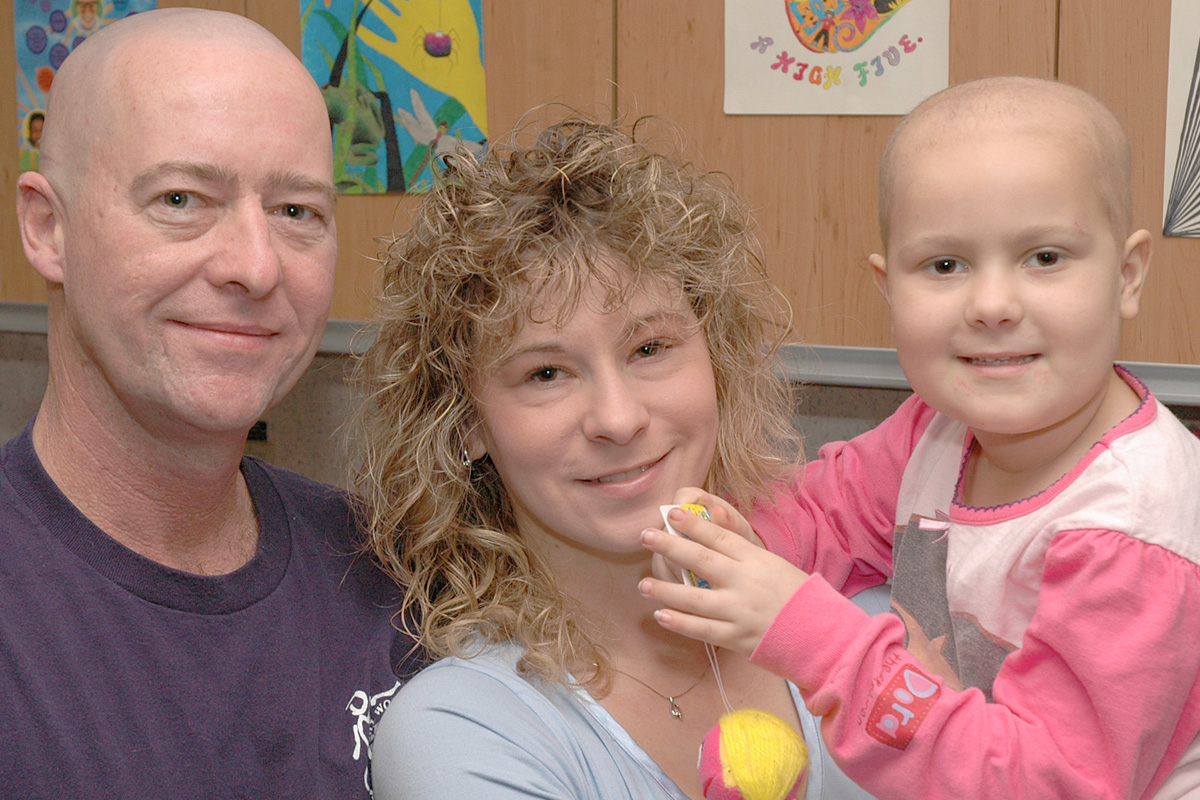 A young girl with childhood cancer with her mother and father.
