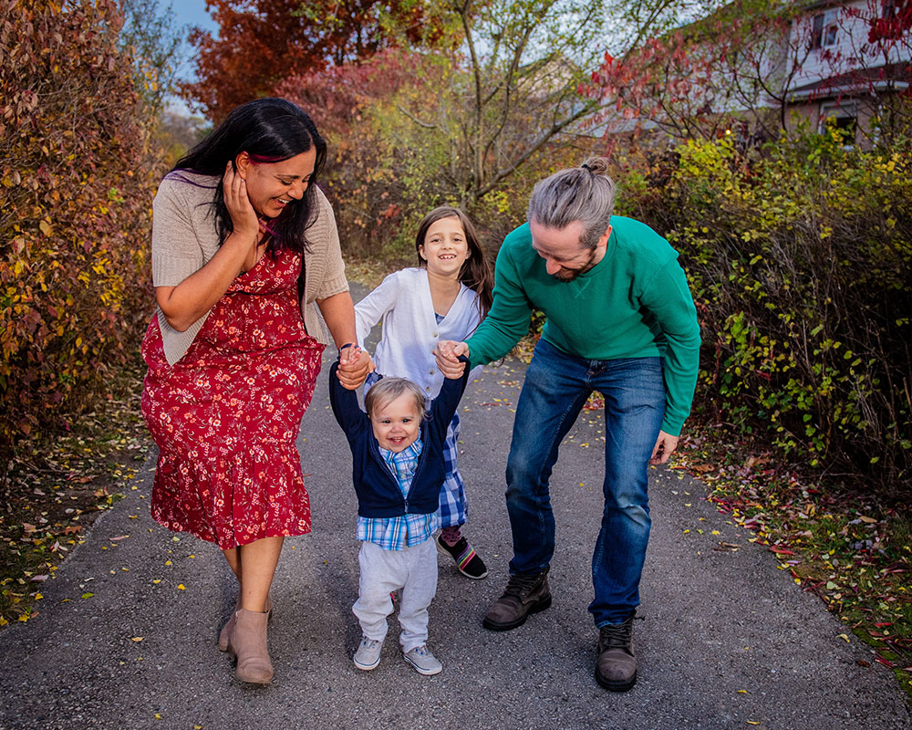 Family of four walking outdoors holding hands in the autumn