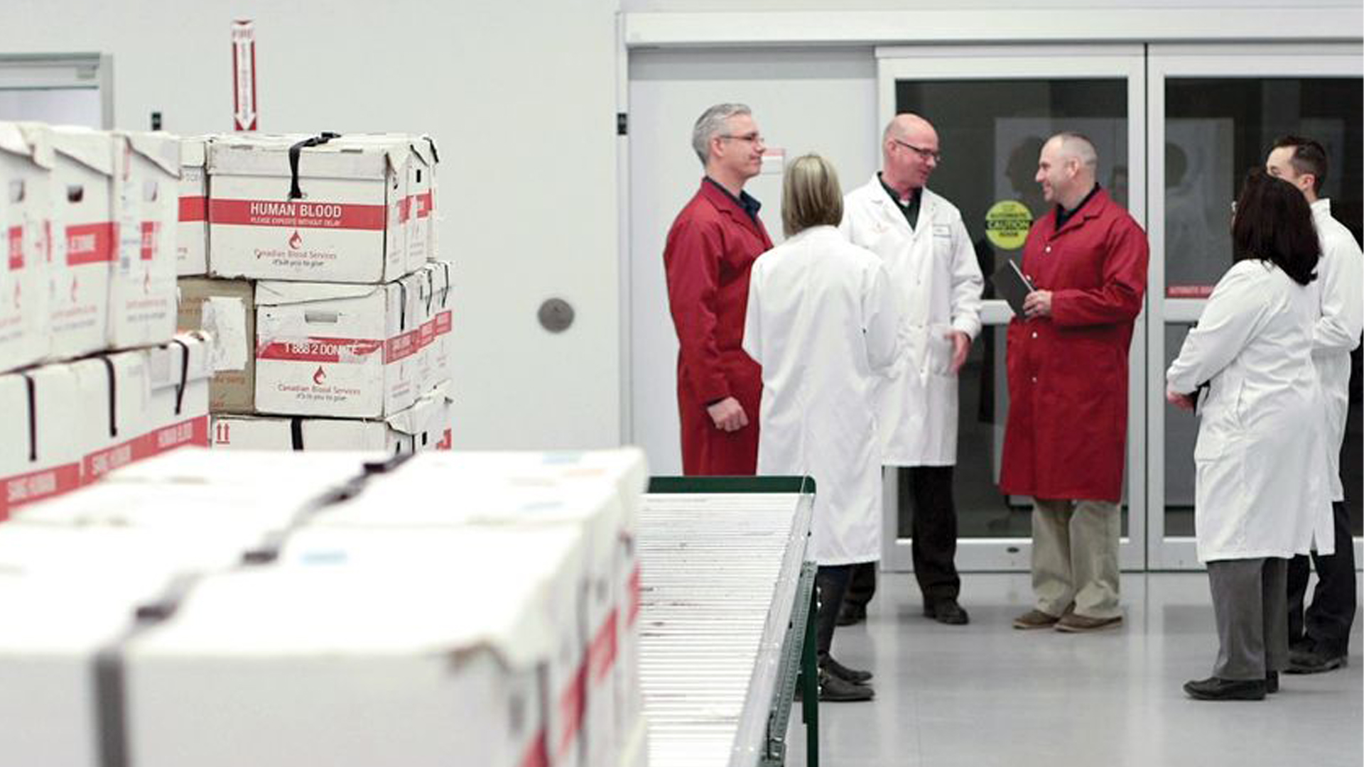 Group of six people wearing lab coats at Canadian Blood Services’ production and distribution facility in Brampton, Ont