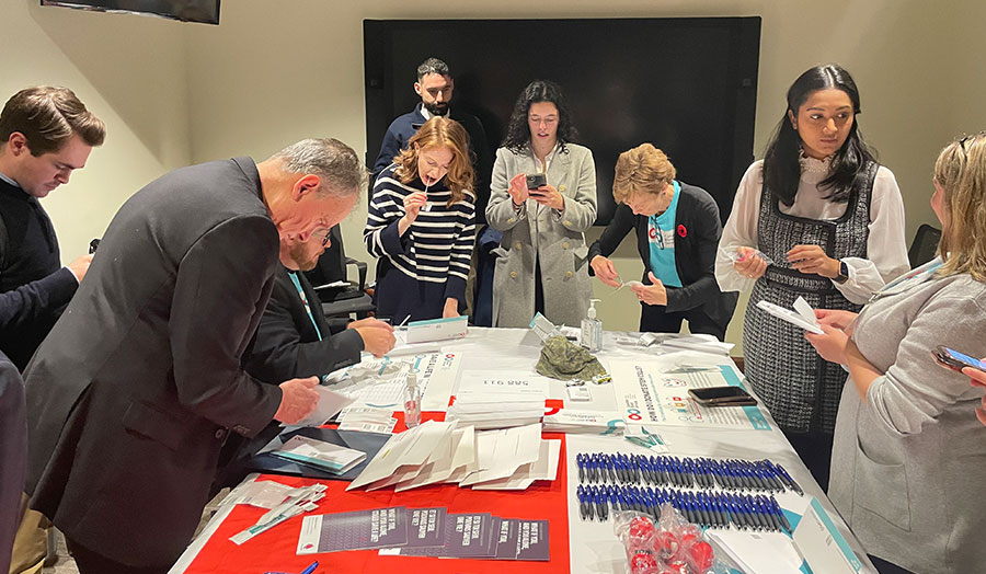 A group of people surrounding a table covered with stem cell registry packages and swab kits.