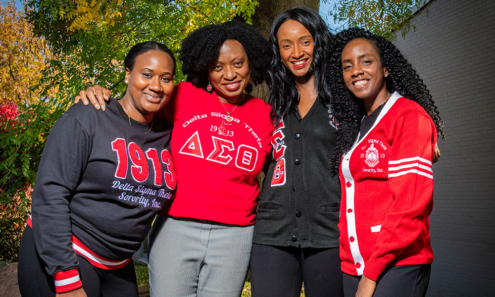 Sorority sisters together outdoors in red and black sorority clothing
