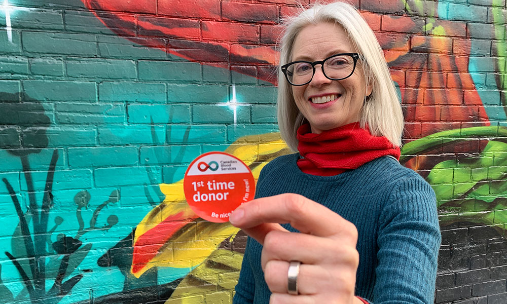 A blood donor holding a first-time donor sticker