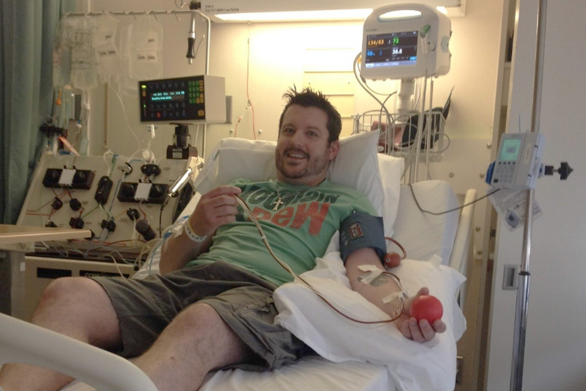 Stem cell donor Joel Menard lies on a hospital bed as stem cells are drawn.