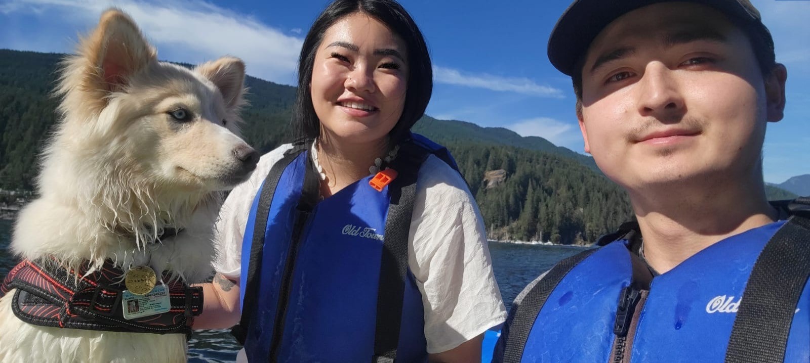 Kumo the dog, Julia and Doug by a lake on a sunny day