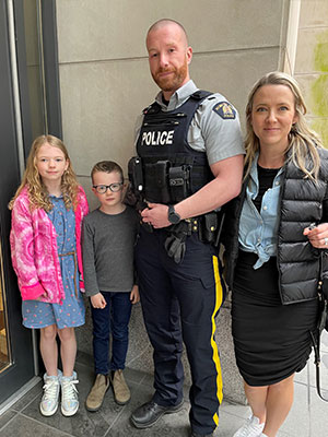 Group photo of a girl, boy, adult male and female by a building entrance