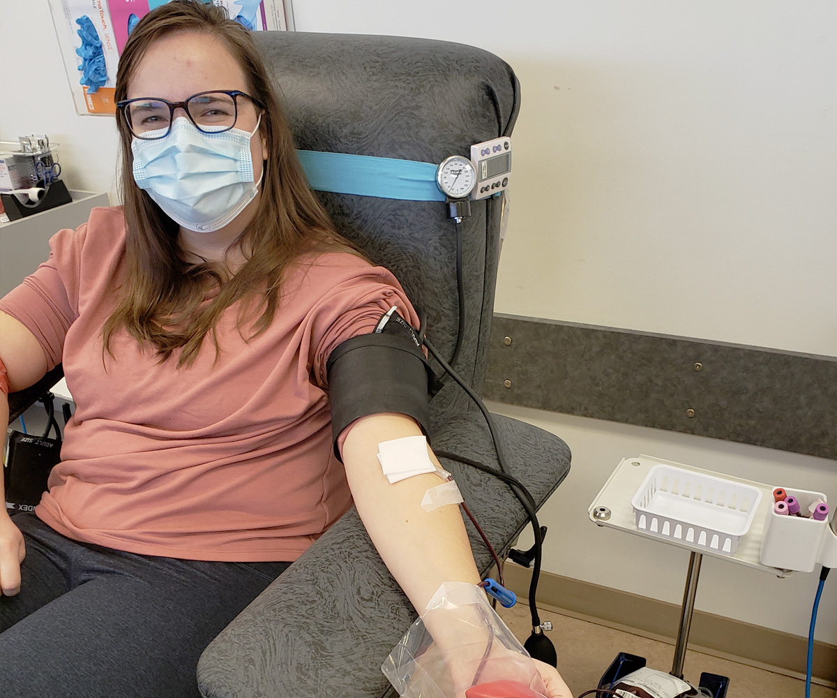 Woman donating blood holding a stress ball next to a blood collection machine