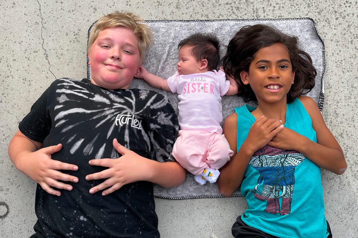Lena Mallary and Cory Greenhalgh’s sons lay on a cement floor with their baby sister.