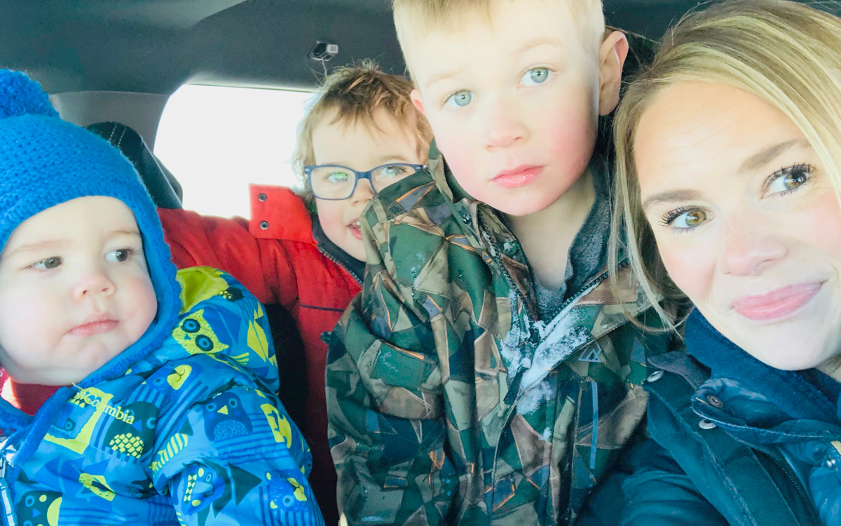 All wearing winter jackets, Lynn Bates and her three sons take a group selfie in her car.