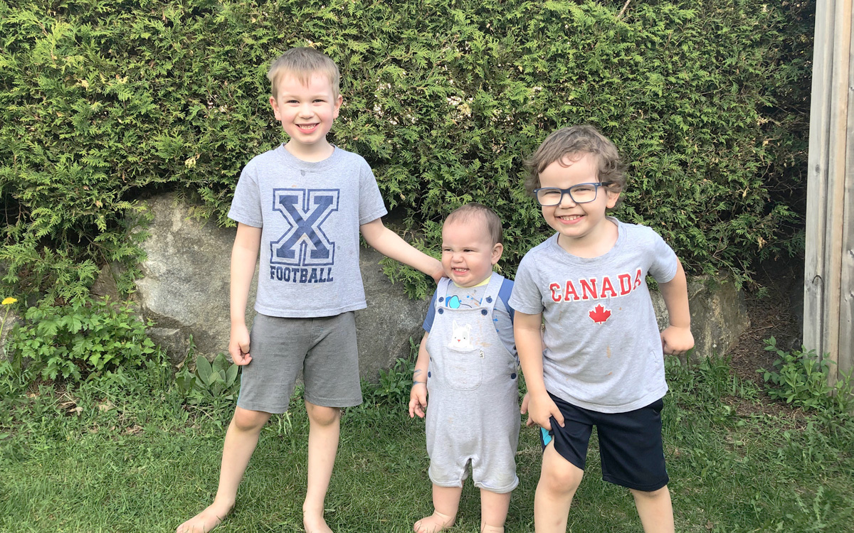 Dressed in casual outfits, cord blood donors Donovan, Evander and Austin smile as they strike a pose in their Ottawa garden.