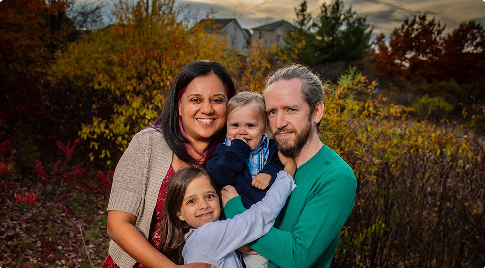 Young family standing together in nature, smiling at the camera