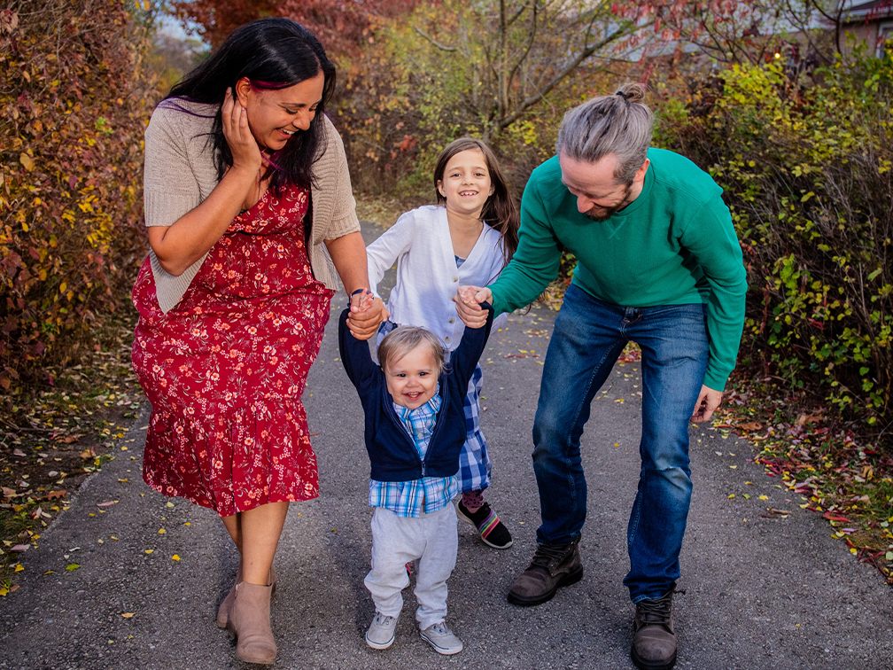 Family of four walking outside holding hands