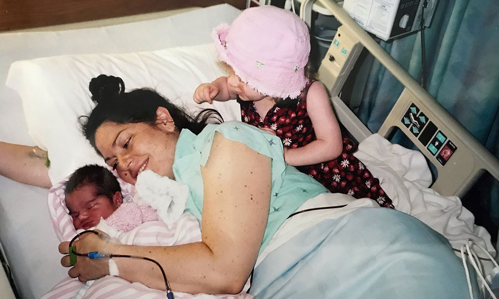 Woman in hospital bed receiving blood transfusion with young children
