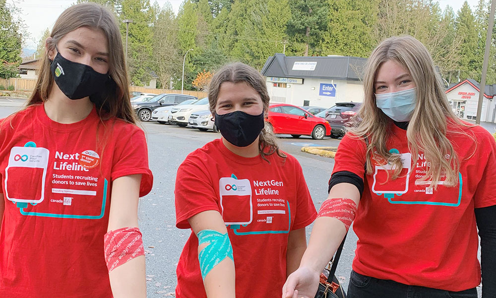 Three blood donors in NextGen Lifeline T-shirts show bandaged arms after blood donation