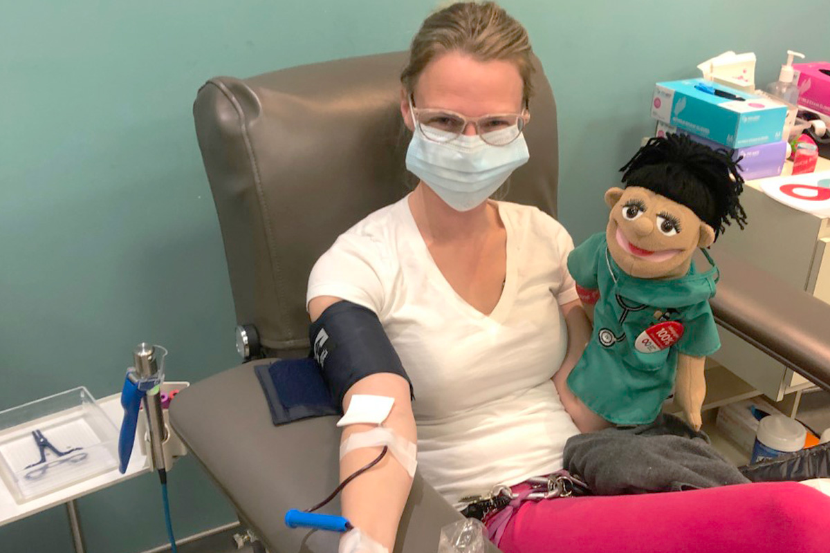Adrienne Chin donating blood holding a puppet