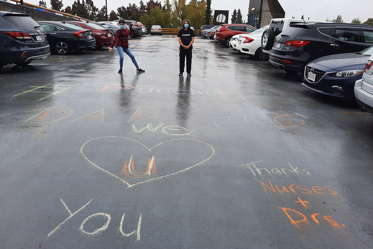 Stem cell recipient’s children pose around chalk signs they had created for their father at his hospital’s car park.