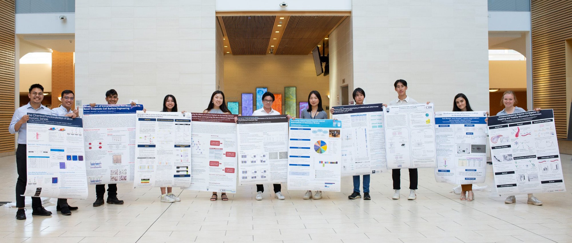 Summer students holding their posters in the Life Sciences Centre West Atrium