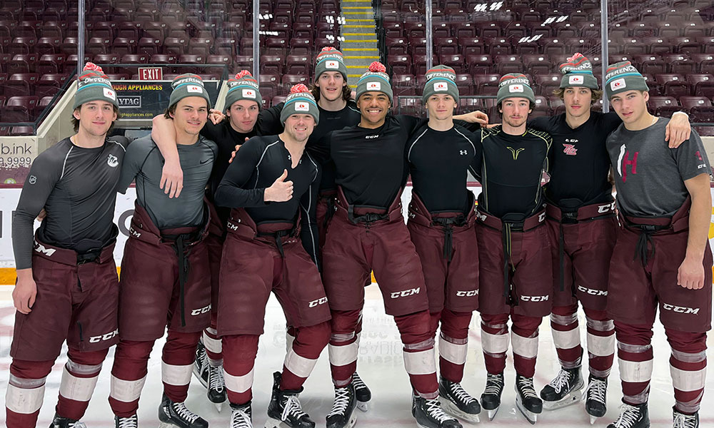 Peterborough Petes hockey team players together on the ice wearing Hockey Gives Blood tuques