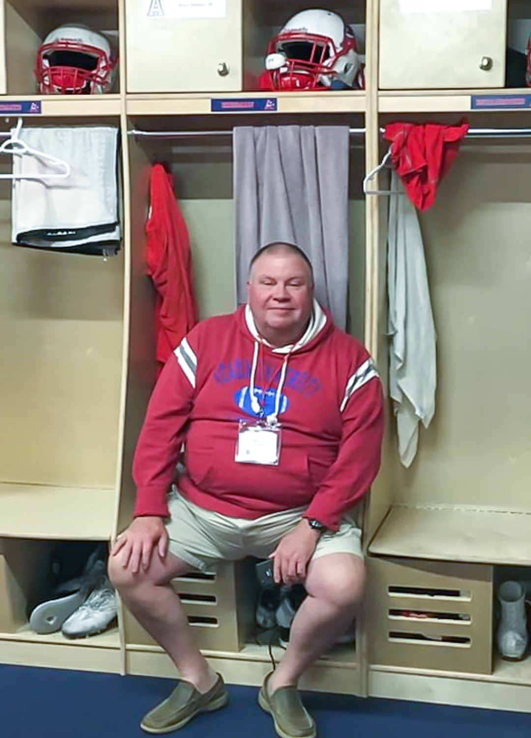 Image of Bruce Phinney in a football locker room sitting on a bench