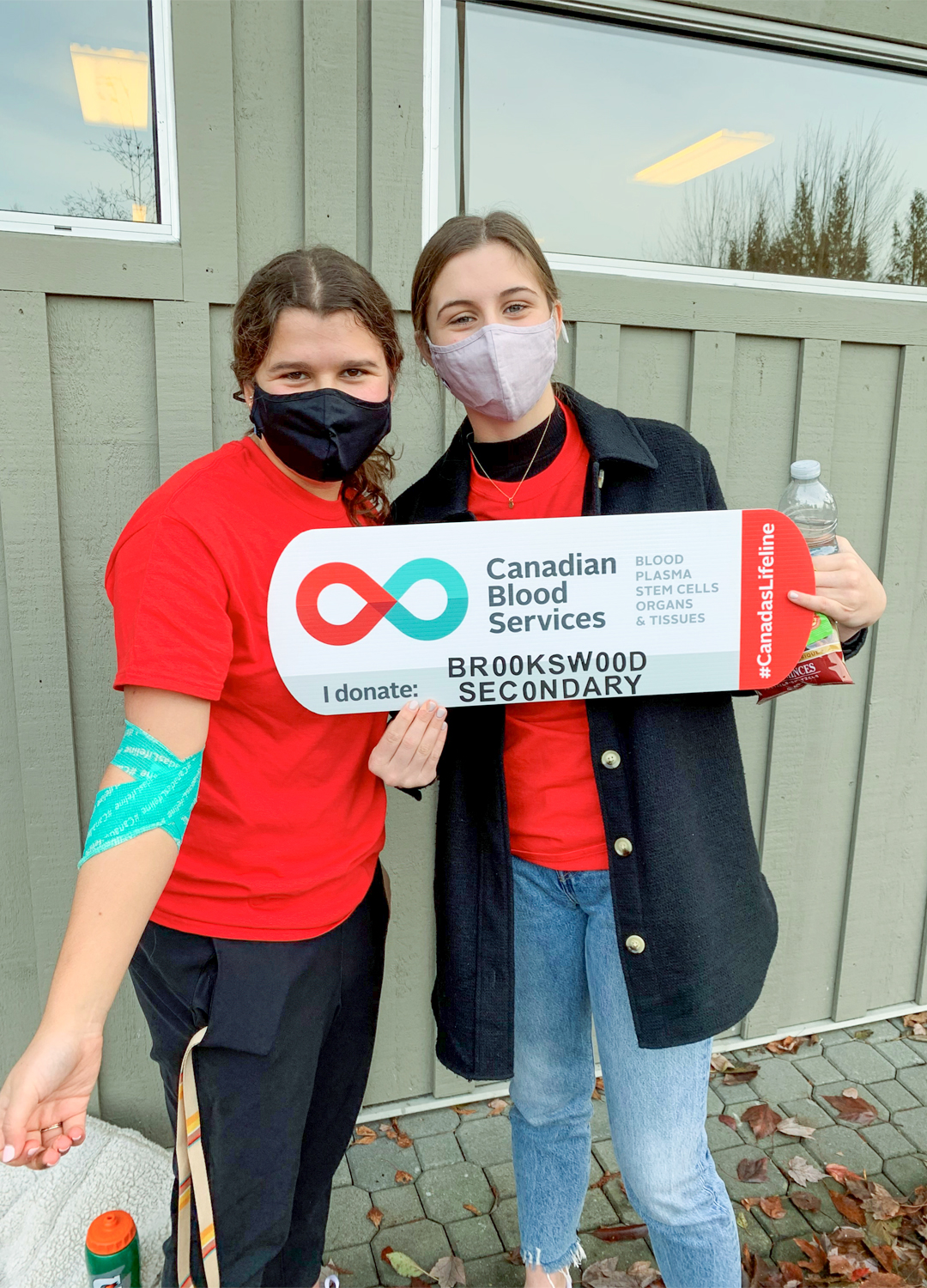 Two girls from Brookswood Secondary School in Langley with sign acknowledging blood donation